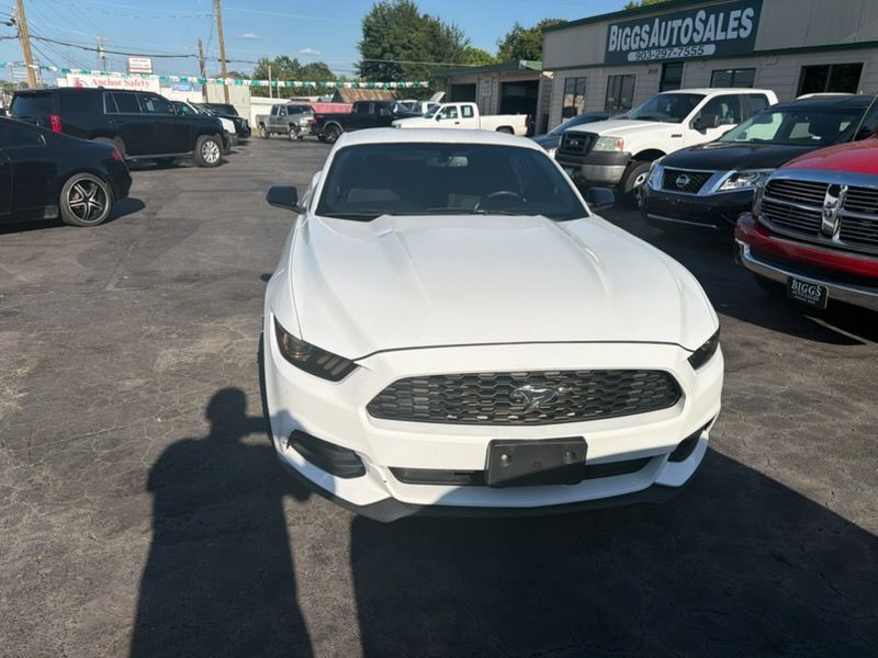 White SUV parked on a dealership lot under bright sun, with rows of cars in the background.