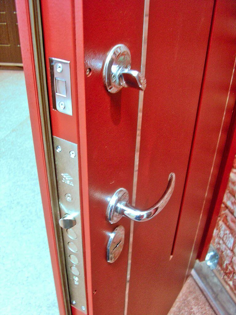 A close up of a red door with a chrome handle