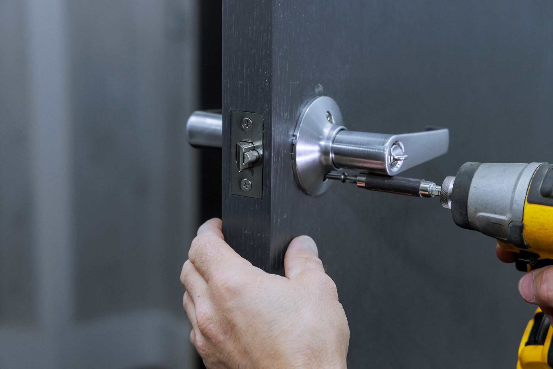 Locksmith installing lock handles on room doors with screwdriver, highlighting locksmith services.