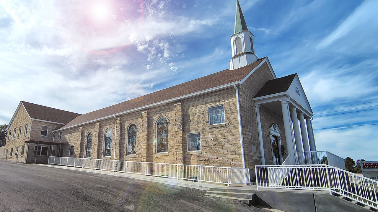 Stone church with steeple and ramp, viewed from the side under a bright blue sky