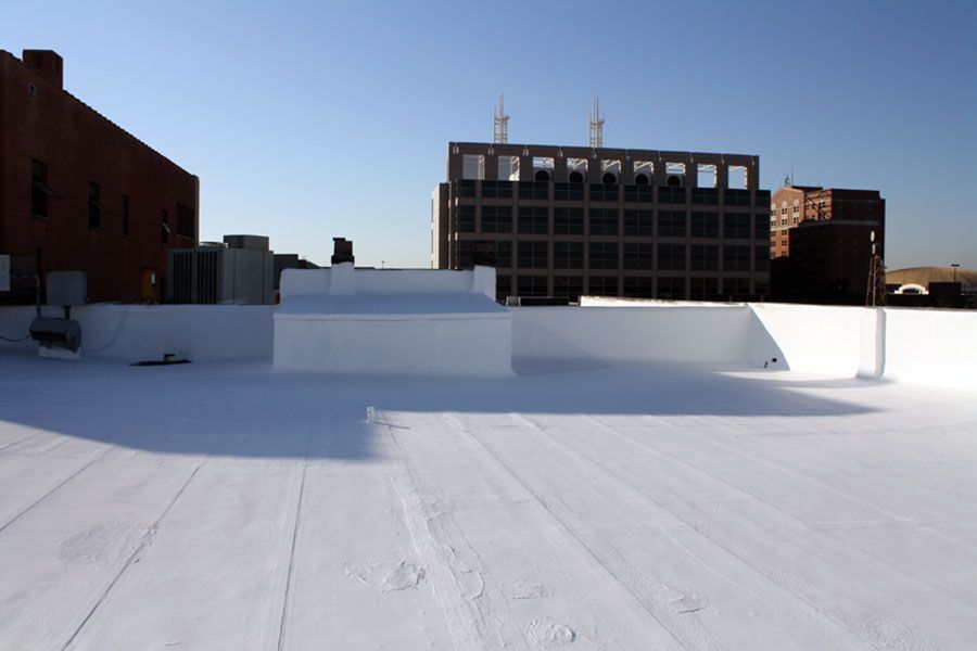 Snow-covered rooftop with low white walls and brick buildings in the background