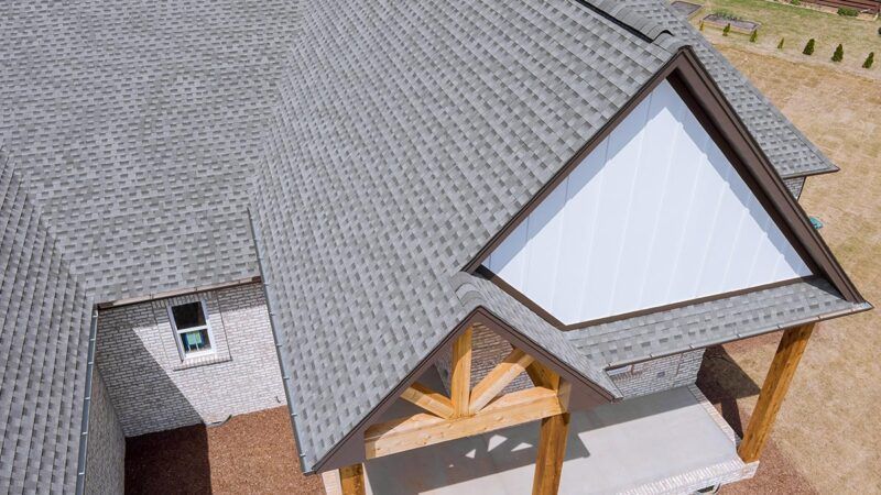 Aerial view of a house roof with gray shingles and a front porch gable
