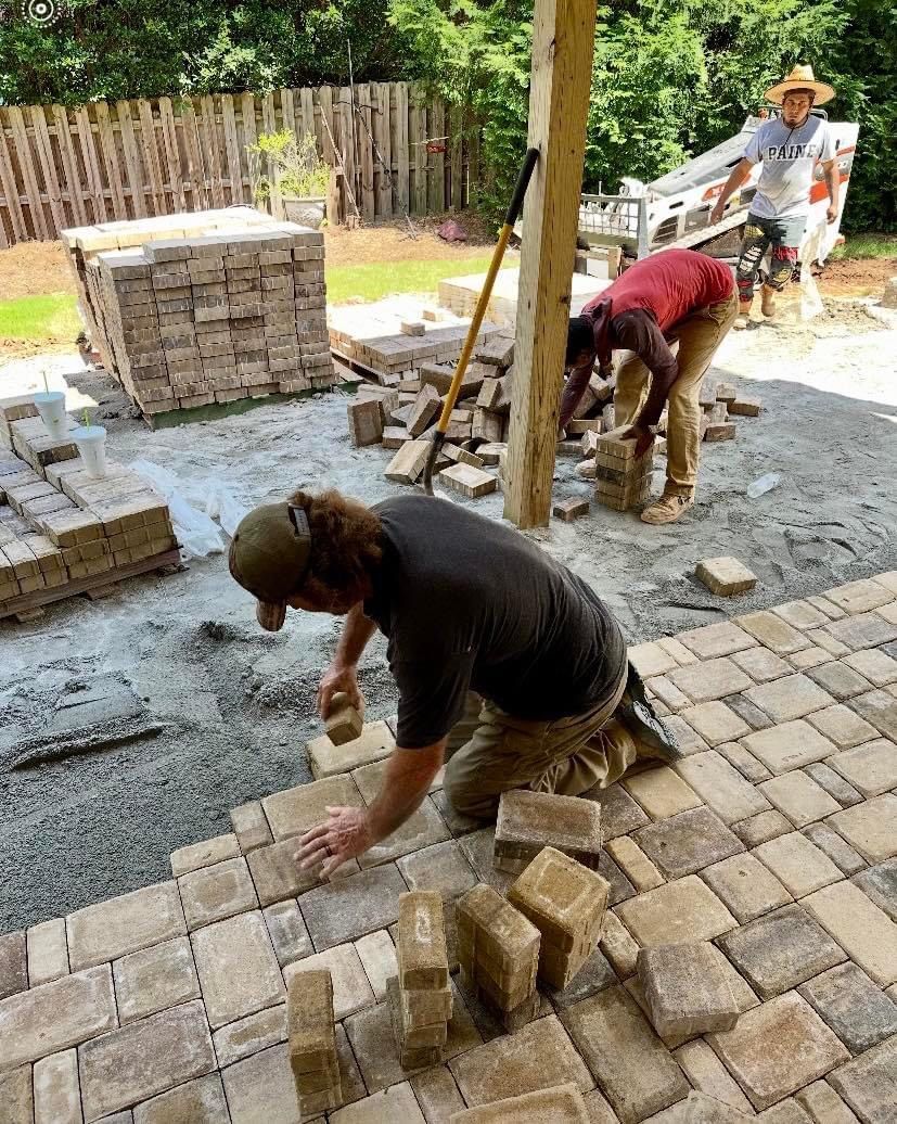A group of men are working on a patio with bricks.