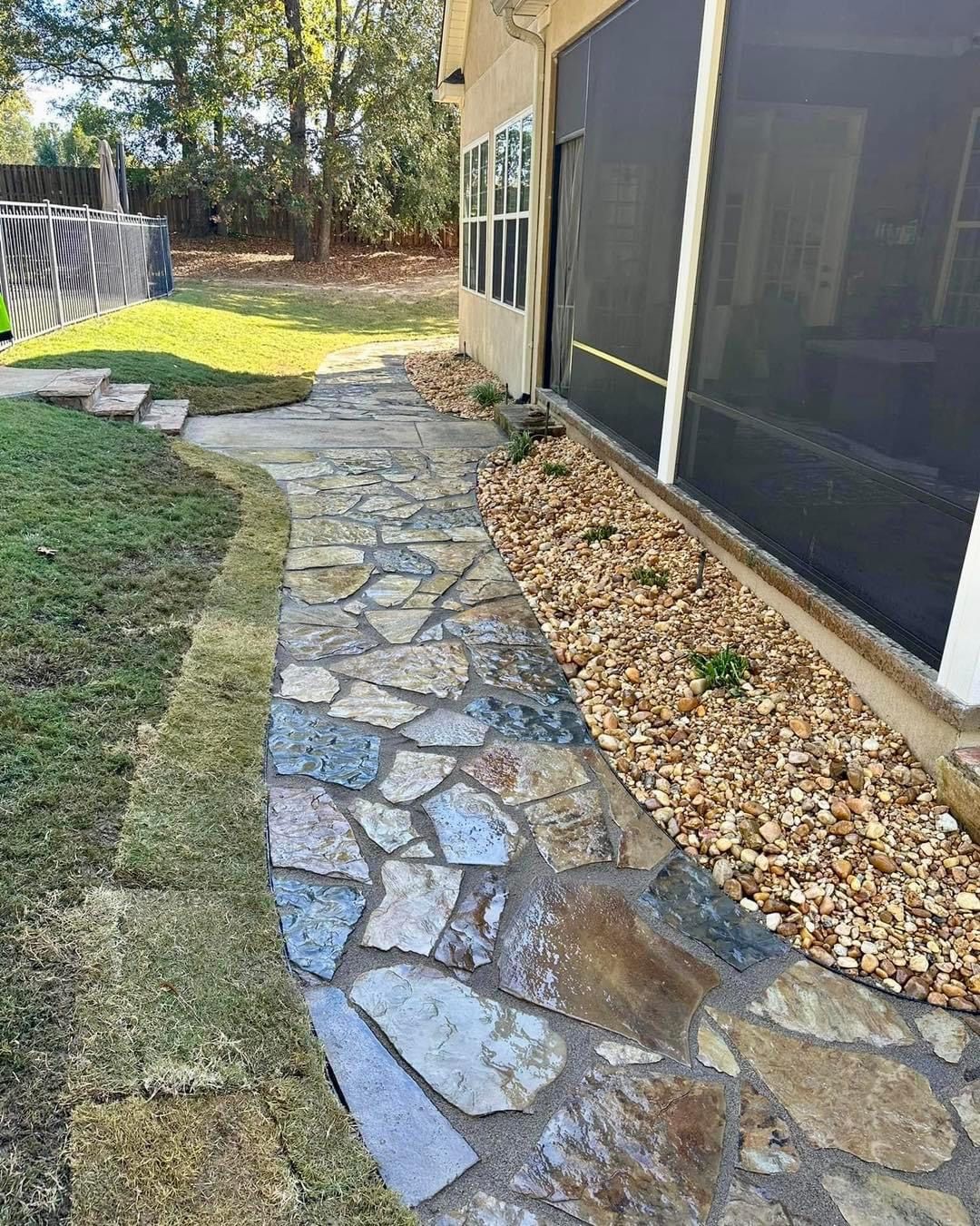 A stone walkway leading to a screened in porch next to a house.