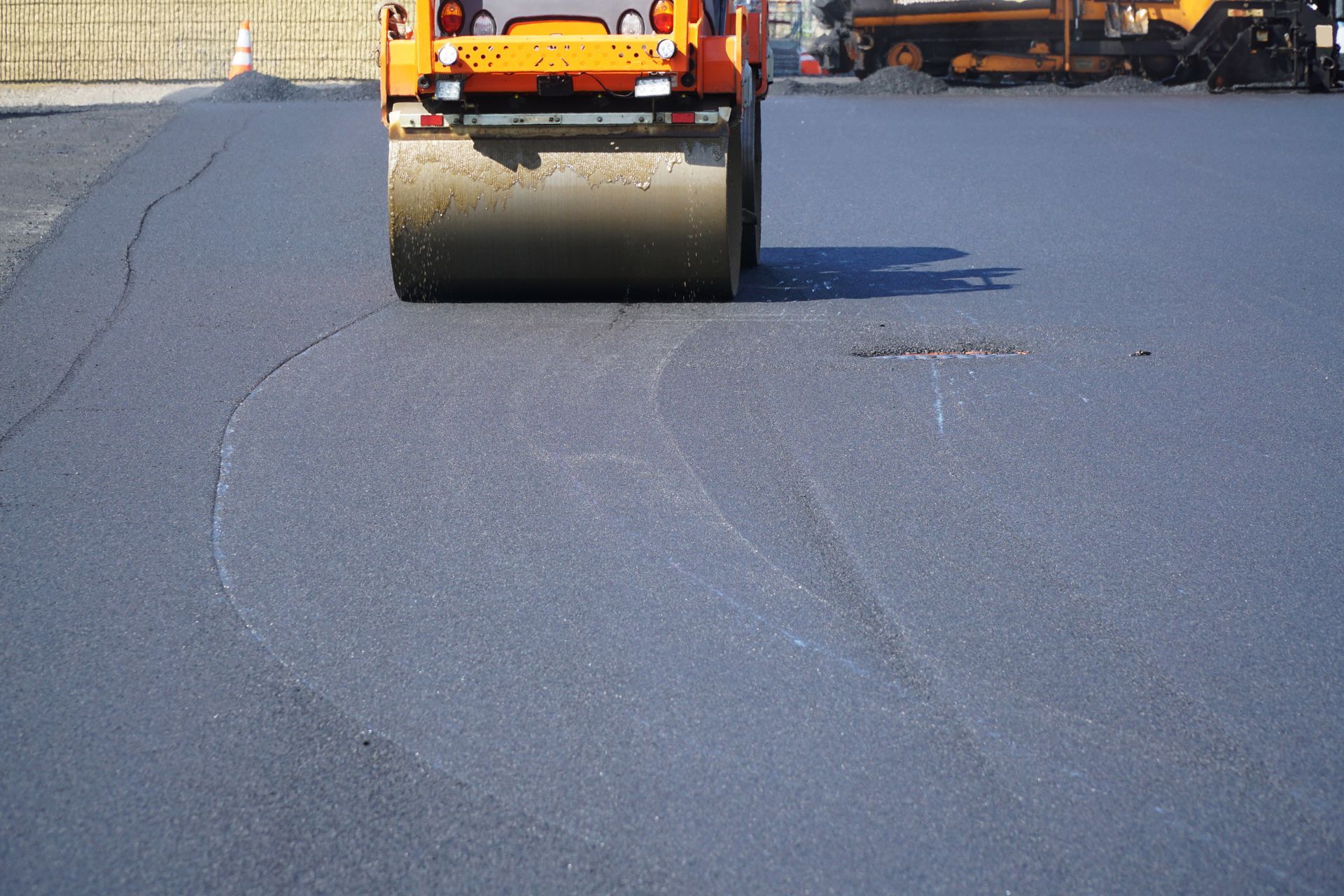 Asphalt roller compacting fresh black asphalt on a road surface. Asphalt roller compacting fresh black asphalt on a road surface.
