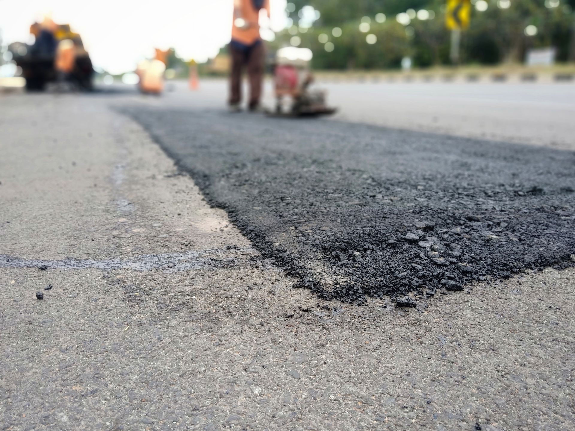 Road resurfacing in progress; workers compacting fresh asphalt on a roadway. Road resurfacing in progress; workers compacting fresh asphalt on a roadway.
