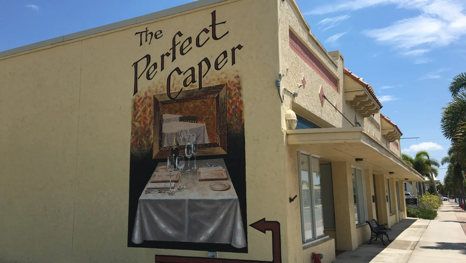 A building with a mural on the side that says the perfect caper