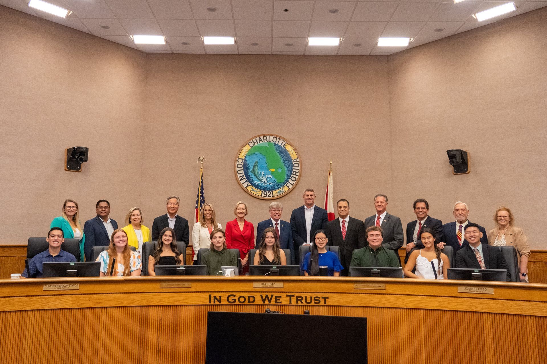A group of people are posing for a picture in a council chamber.