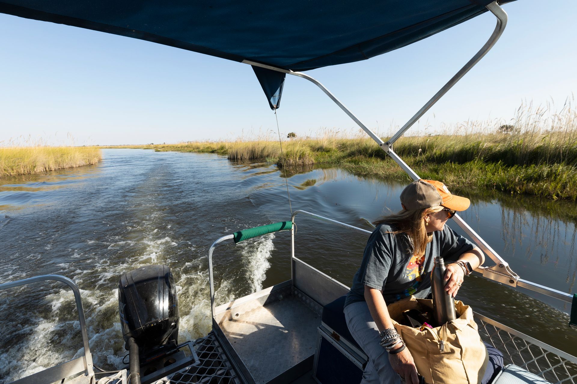 A woman is sitting on the back of a boat on a river.