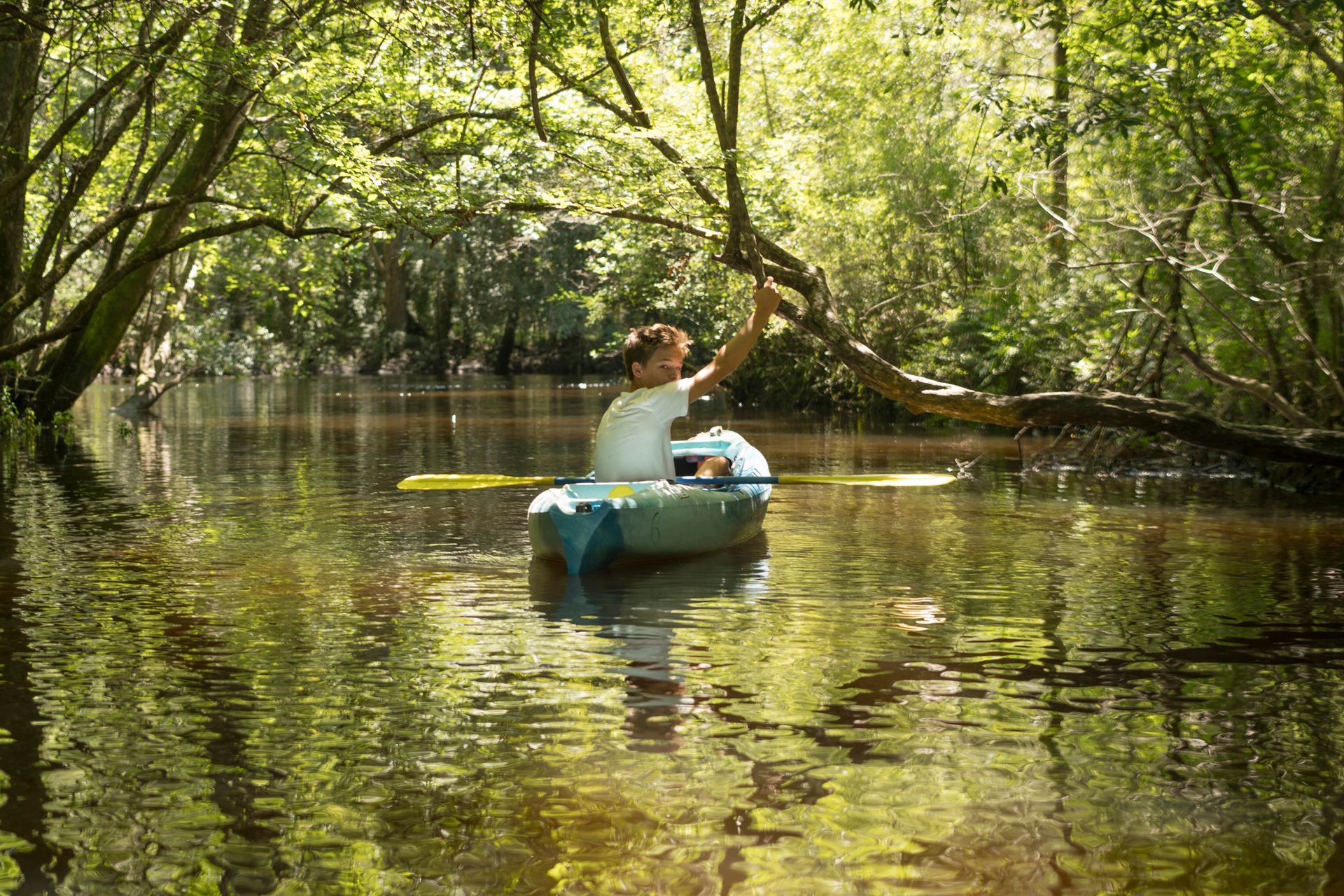 A man is paddling a kayak down a river.