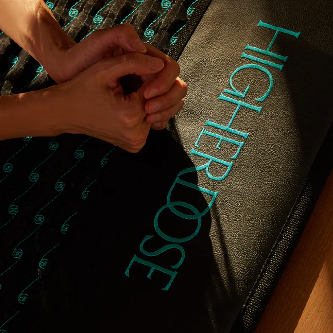 Hands clasped on top of a PEMF Mat by Higher Dose