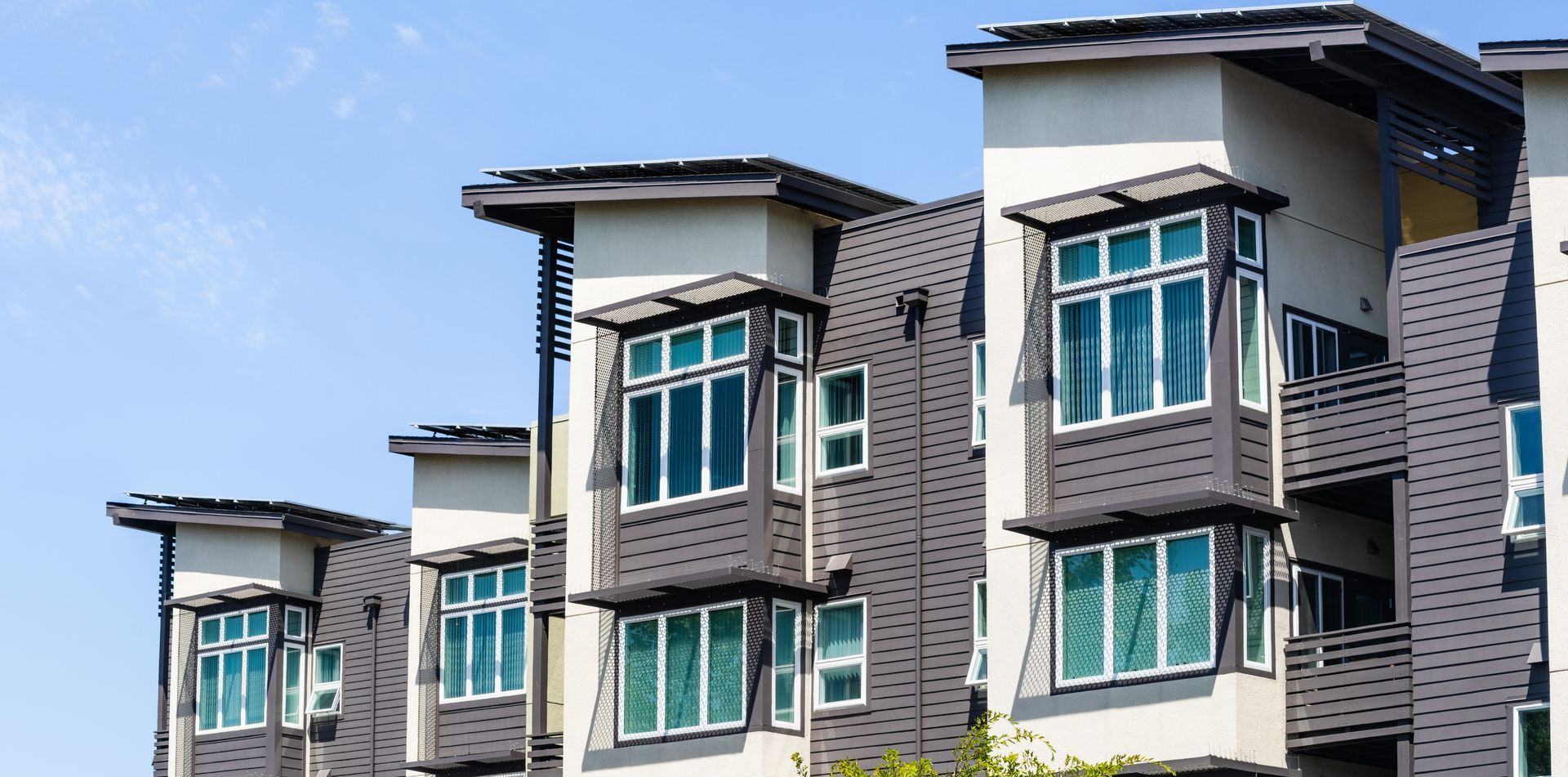 Modern multi-unit apartment building against a blue sky.
