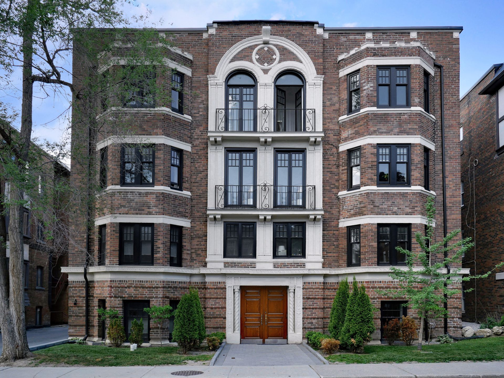 Brick apartment building with arched details, dark windows, and ornate entry doors.