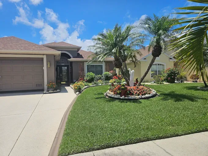 Suburban house with a two-car garage, green lawn, and landscaped front yard under a clear sky