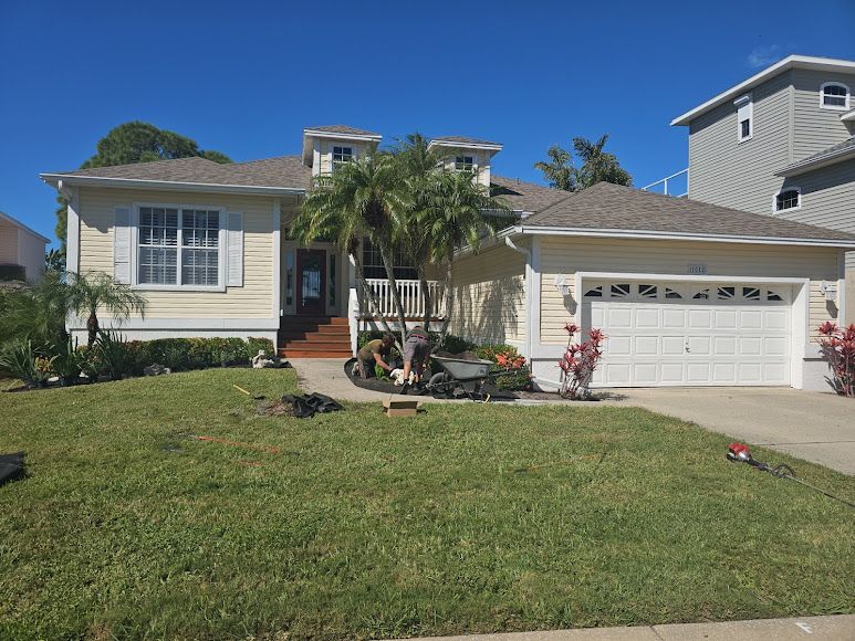 Suburban house with attached garage, front lawn, and palm trees under a clear blue sky