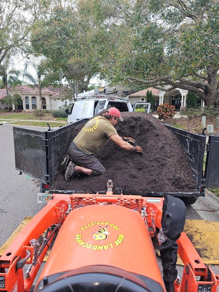 Worker loading dirt into a trailer behind an orange machine on a residential street
