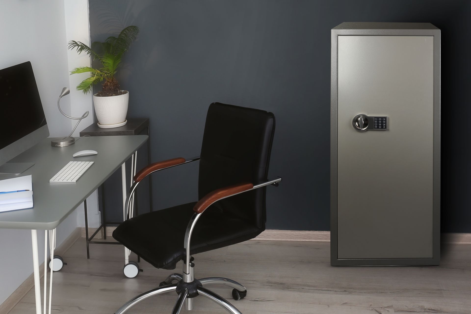 Modern office with desk, black chair, potted plant, and gray metal safe against the wall