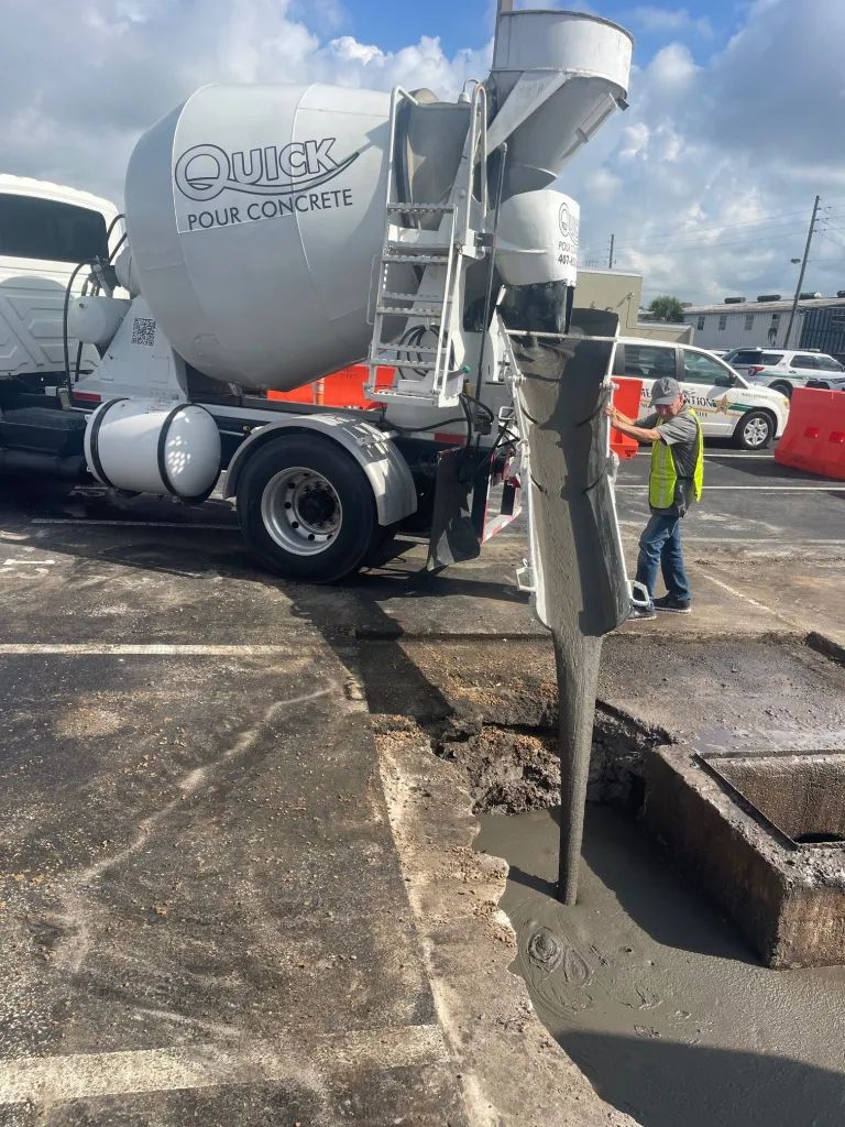Concrete truck pouring concrete into a construction site. Worker watches.