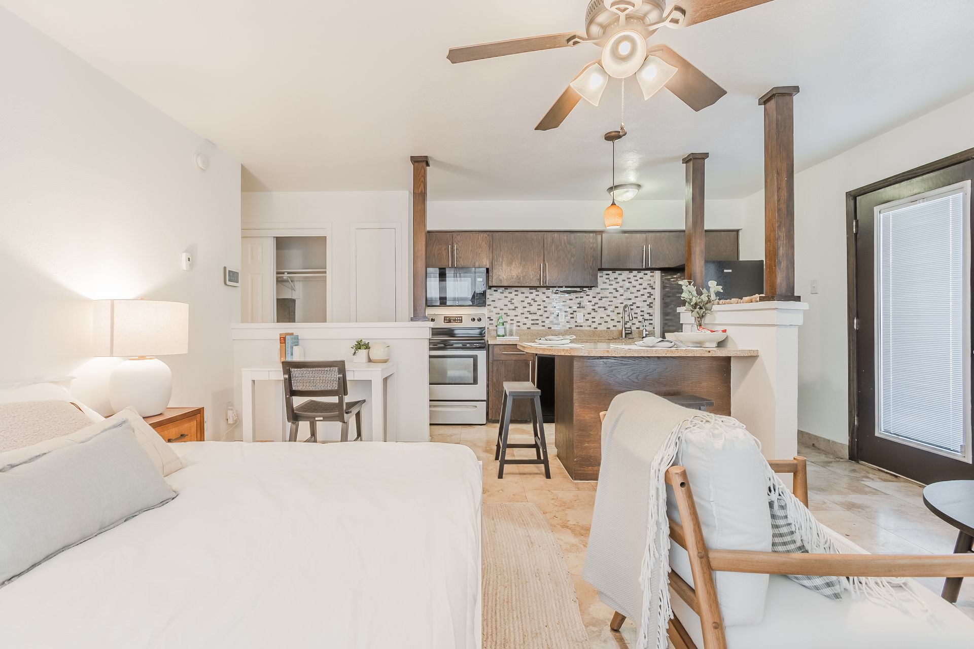 Photo of a studio, showing a bed, with the dining area in the middleground and a kitchen in the background