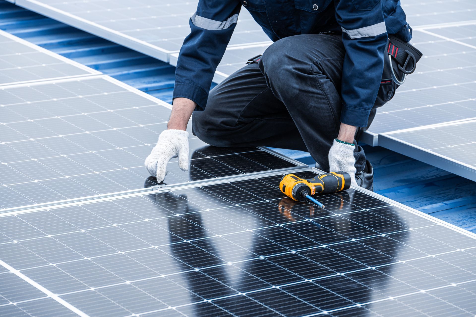 Technician cleaning solar panels with a cloth and tool on a rooftop array