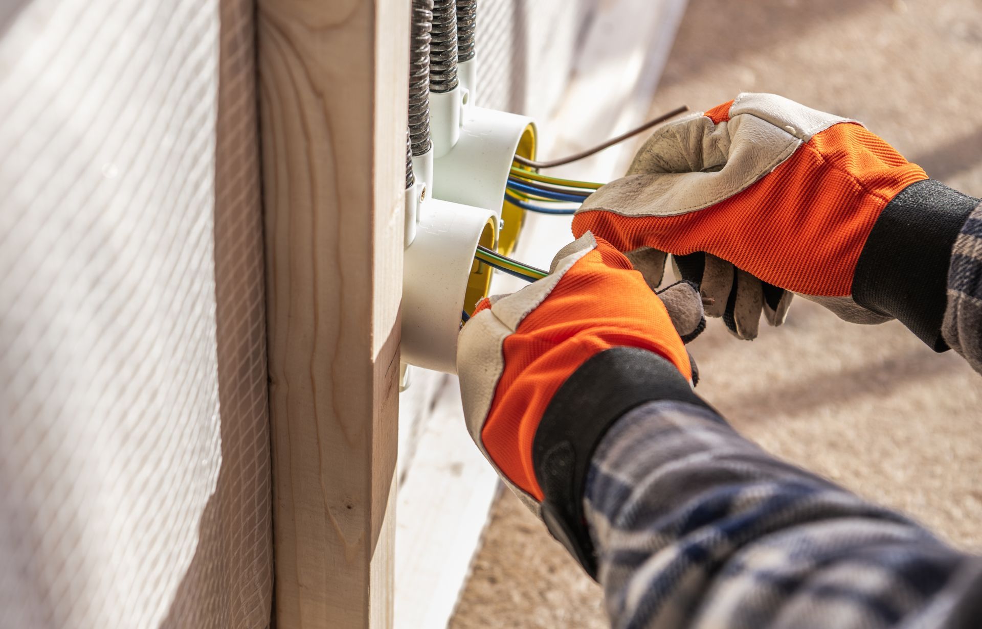 Gloved hands measuring a doorway with a tape measure beside white siding