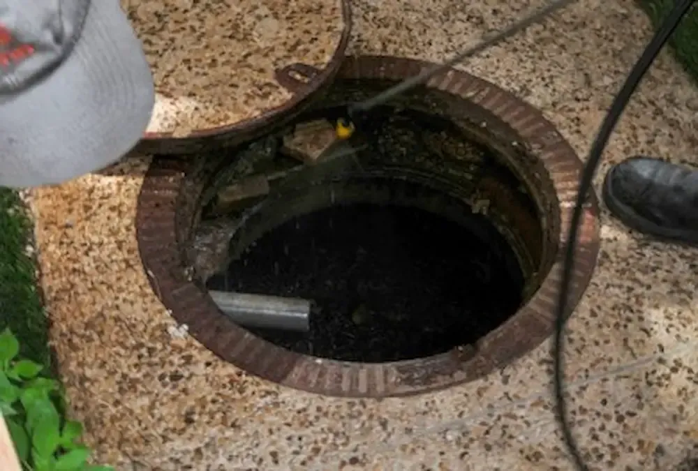 Open manhole on a speckled floor with a person’s foot nearby