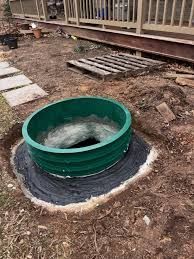 Green plastic tub filled with churning water set in a dirt yard beside a wooden deck