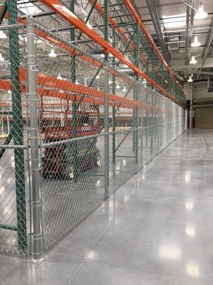 Chain-link fence separating warehouse storage racks and floor space.