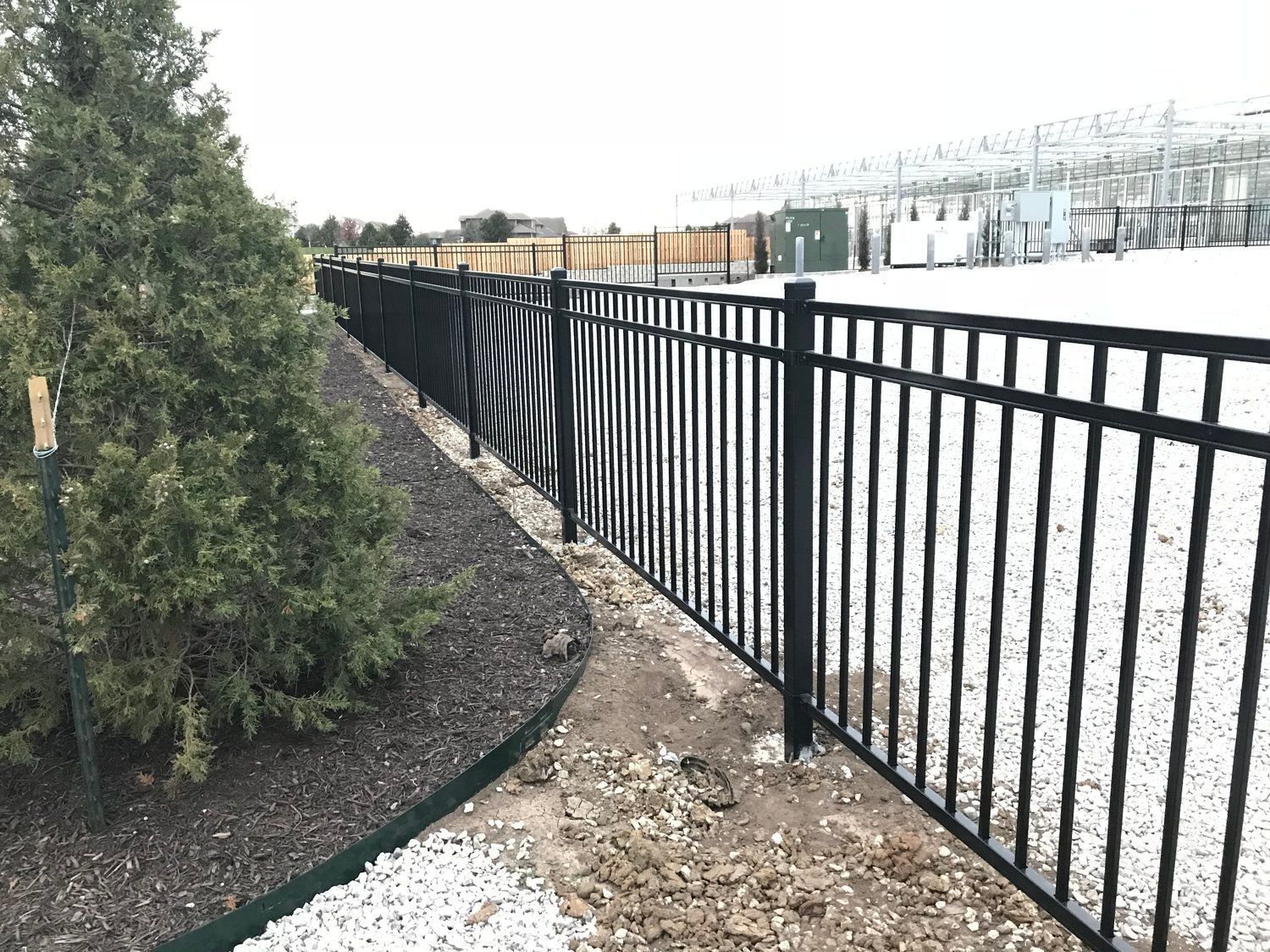 Black metal fence curves along a landscaped area.