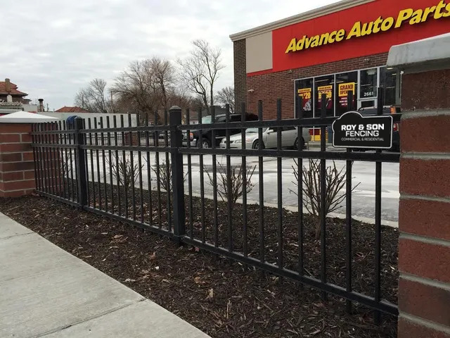 Black metal fence bordering Advance Auto Parts store, brick pillars on each side.