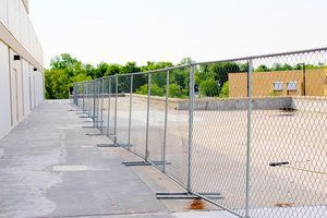 Chain-link fence along a concrete walkway, separating it from a construction site.