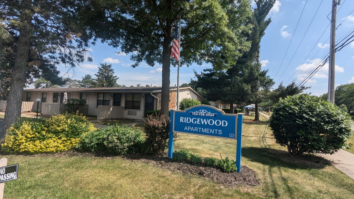 A blue sign is sitting in front of a house.