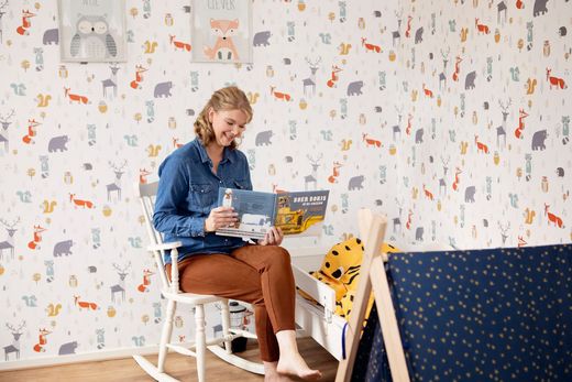 Jong kind met koptelefoon kijkt omhoog in een kamer met een televisie en een boekenkast.