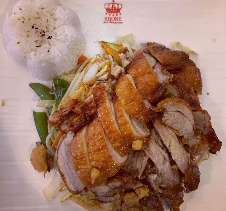 ein weißer Teller mit einem Stück Fleisch und Reis darauf .