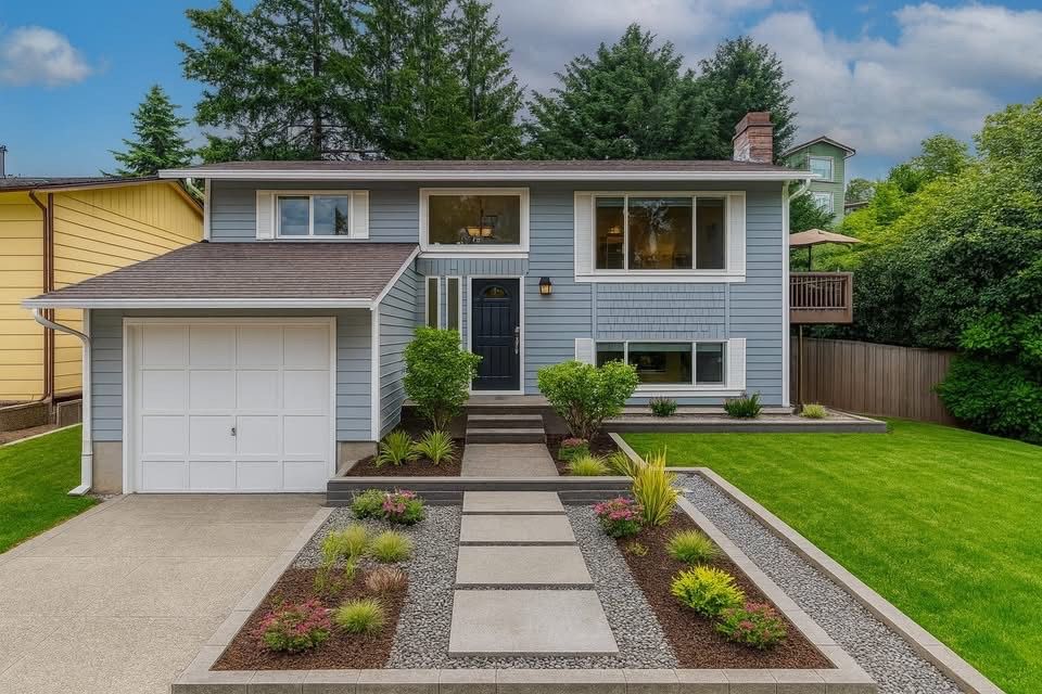 Suburban split-level house with gray siding, white garage, and landscaped front walkway.
