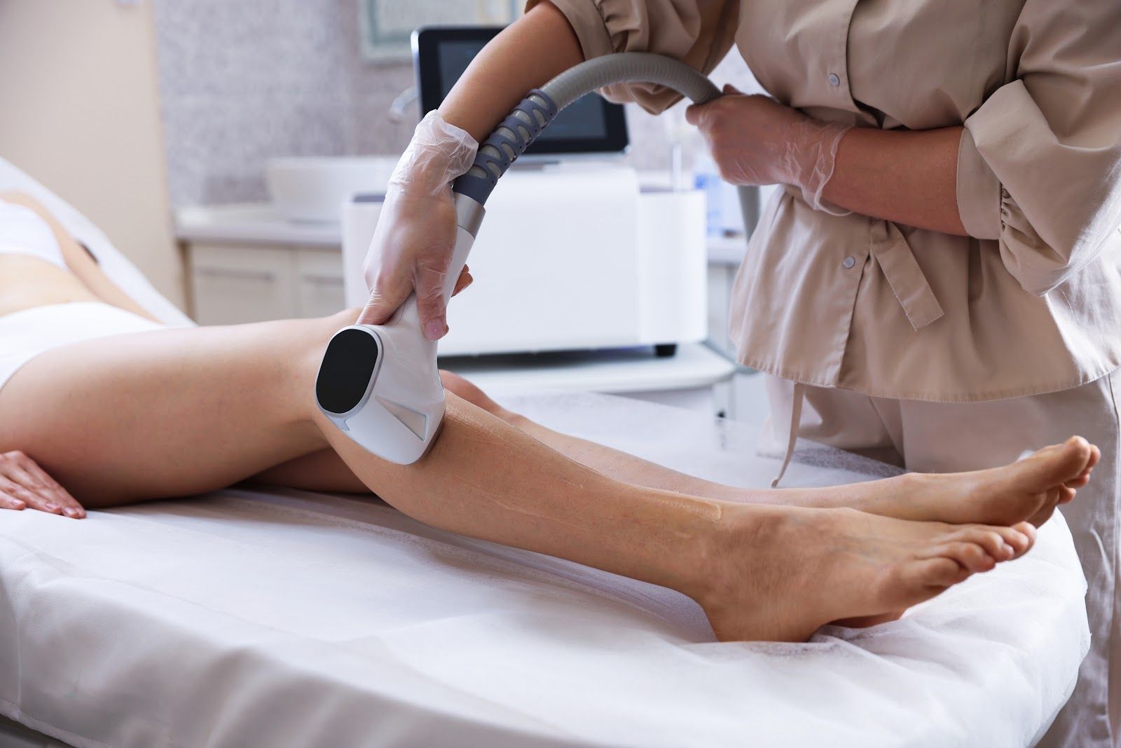 Legs on treatment bed while a clinician uses a handheld device on the calf