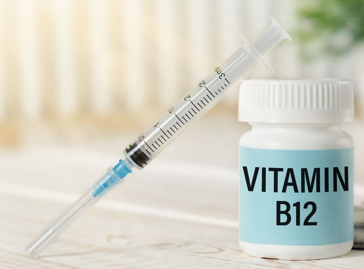 A bottle of vitamin b12 next to a syringe on a table.