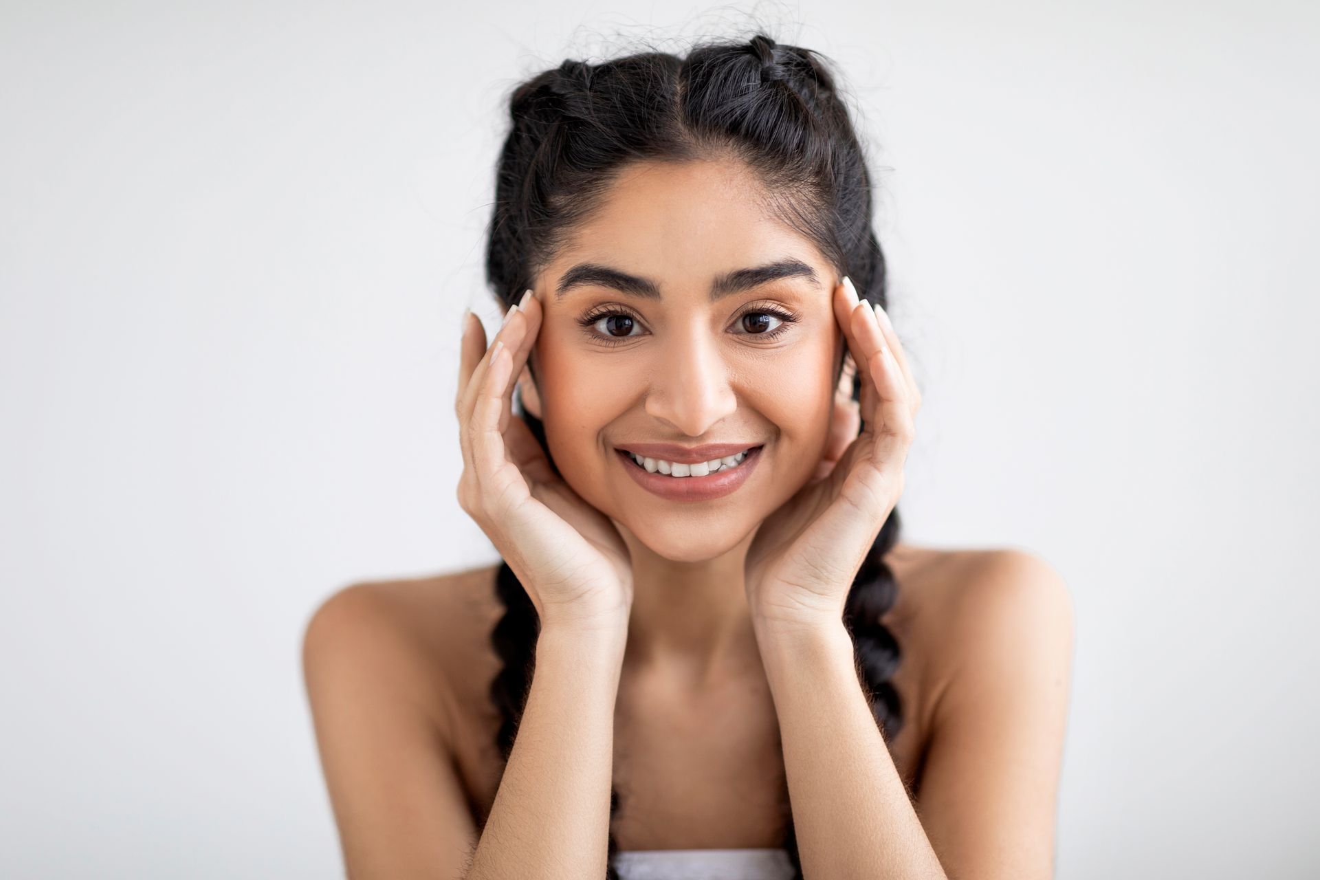 girl smiling at camera holding her face