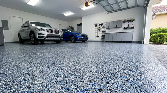 A two-car garage with a speckled epoxy floor featuring a silver SUV and a blue sedan parked inside.