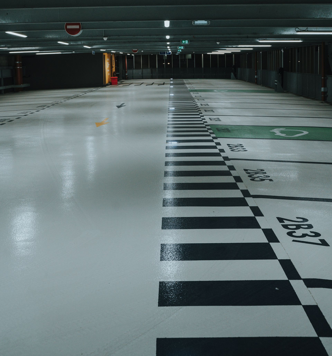 A parking garage floor with painted black-and-white stripes and numbered parking bays.