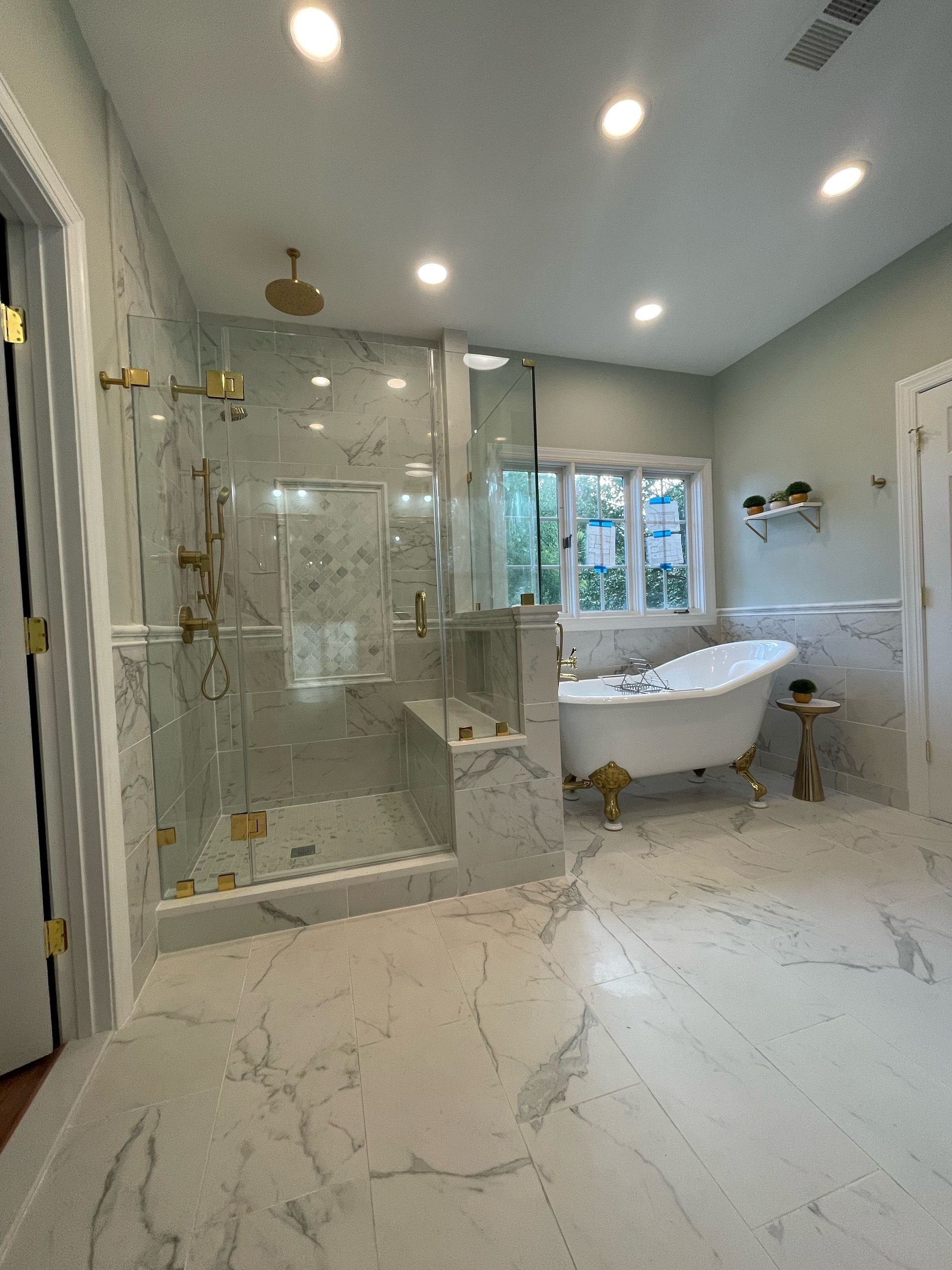 Luxurious bathroom with marble, gold fixtures, and clawfoot tub.