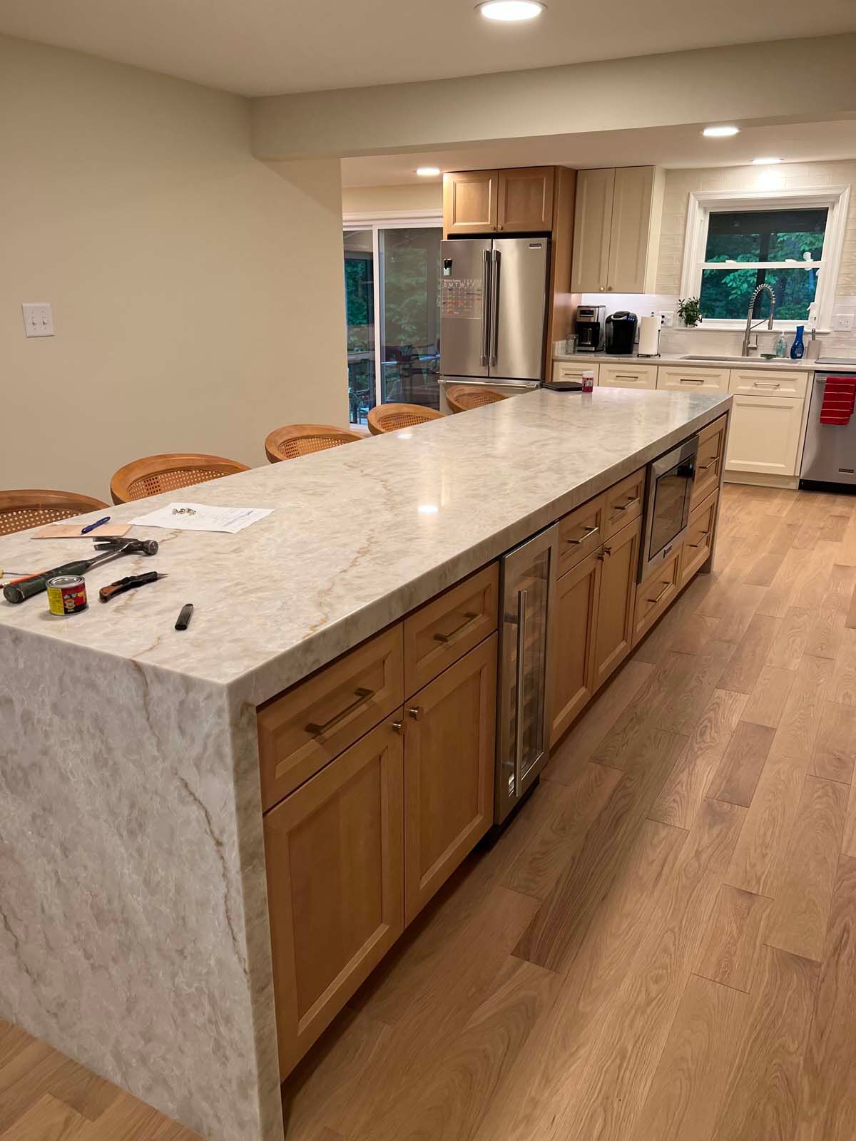 Kitchen island with light wood cabinets, marble countertop, and built-in appliances.
