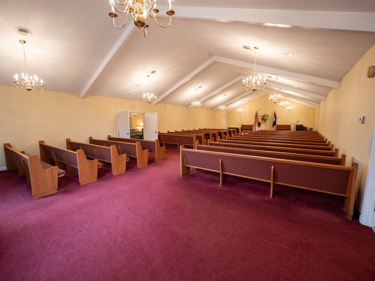 Interior of a church with rows of pews and hanging lights.