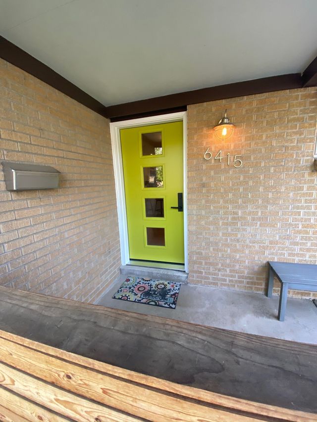 Lime green front door with square windows on a brick house.  Address numbers 