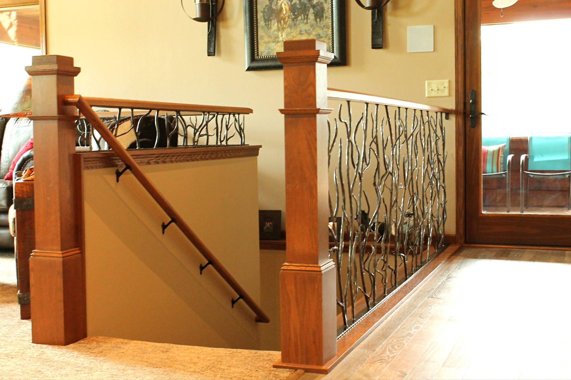 Staircase opening with wooden posts, black handrail, and decorative metal railing in a home interior