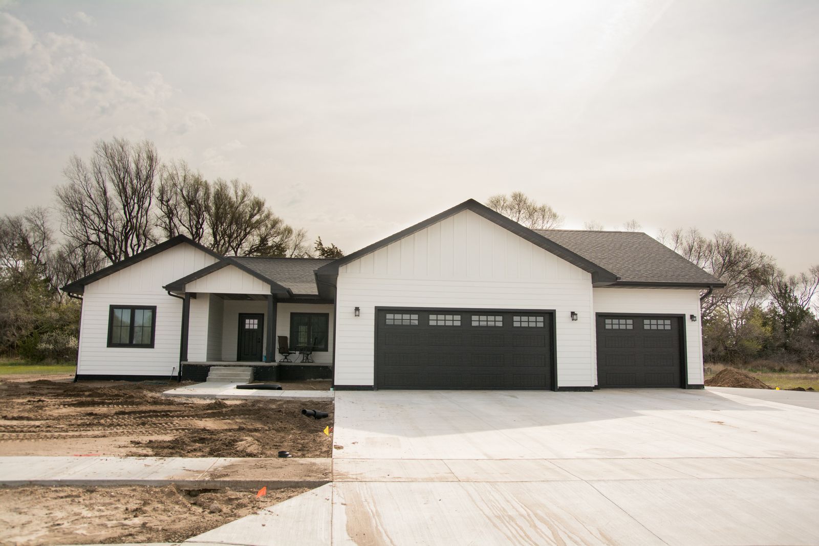 New white house with black garage doors and front porch on a concrete driveway
