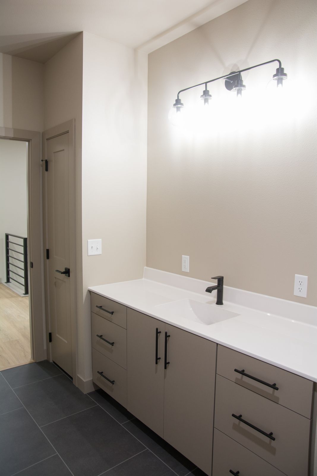 Modern bathroom vanity with white countertop, gray cabinets, mirror, and three-light fixture.