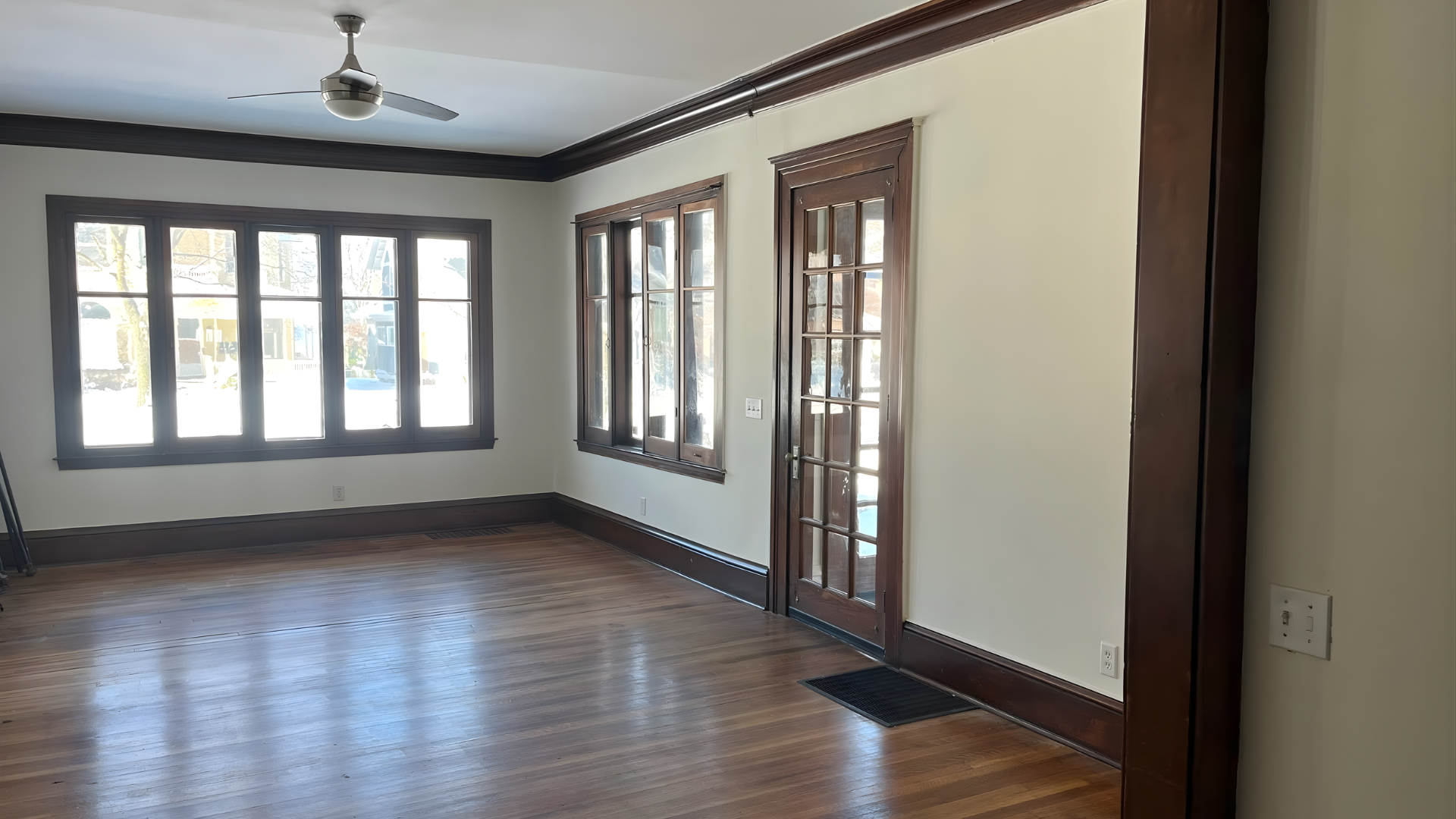 Wooden front door in a small hallway with light walls and wood flooring.