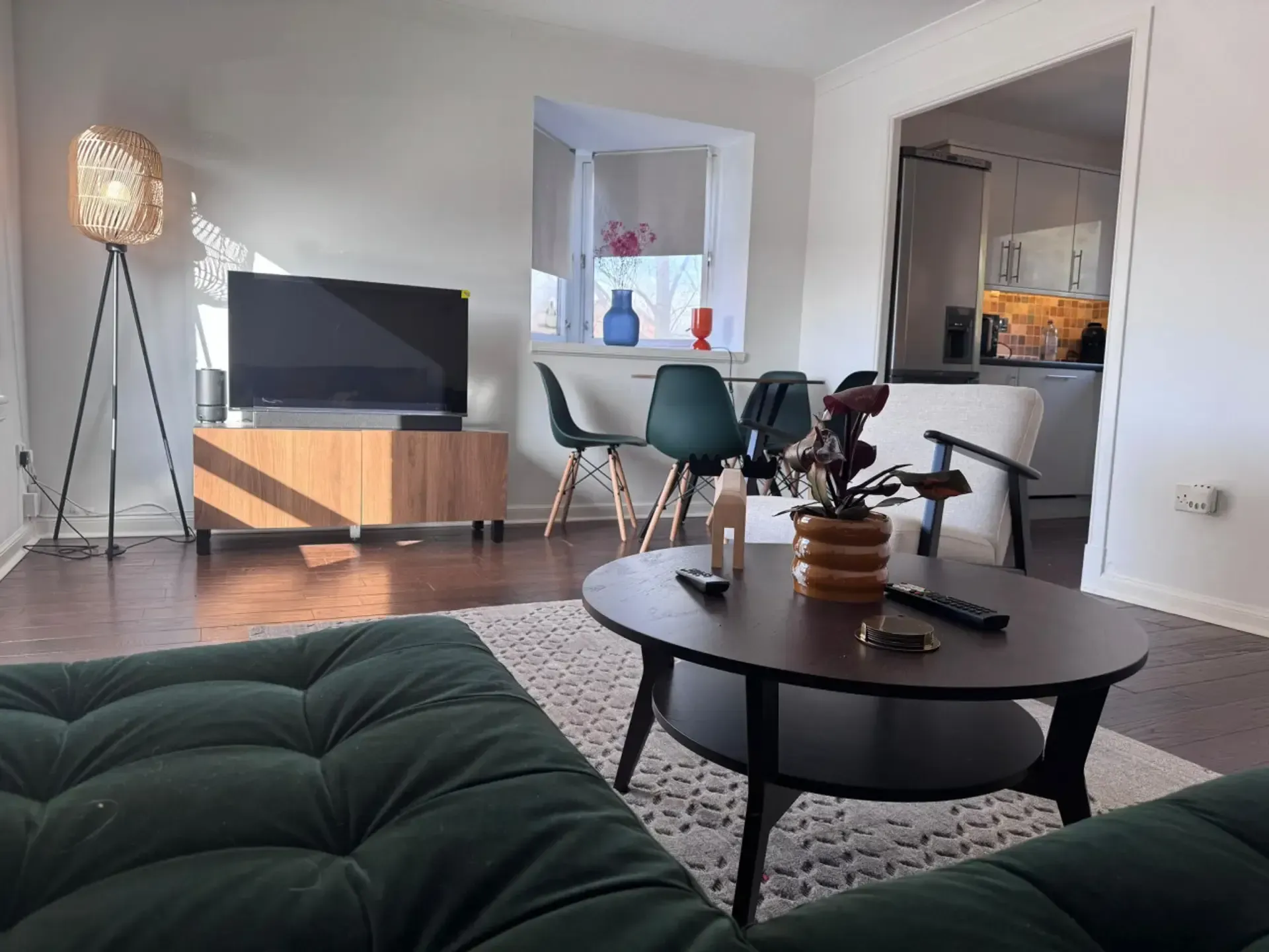 Modern living room with TV, chairs, round coffee table, patterned rug, and floor lamp