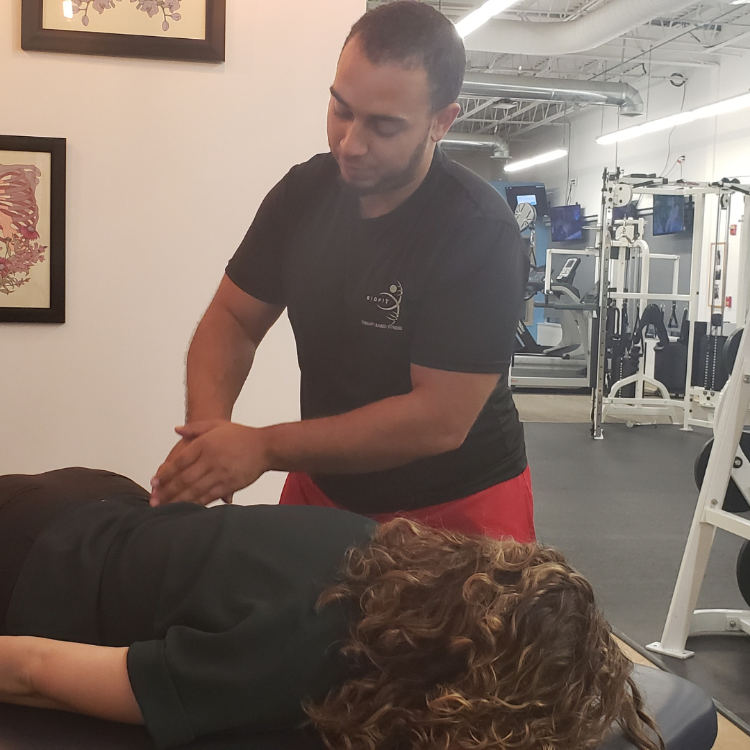 A man is giving a woman a adjustment in a gym.